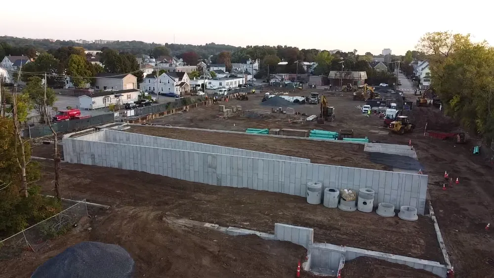 Aerial view of early-stage construction at Avalon Quincy site showing concrete foundation walls and heavy equipment